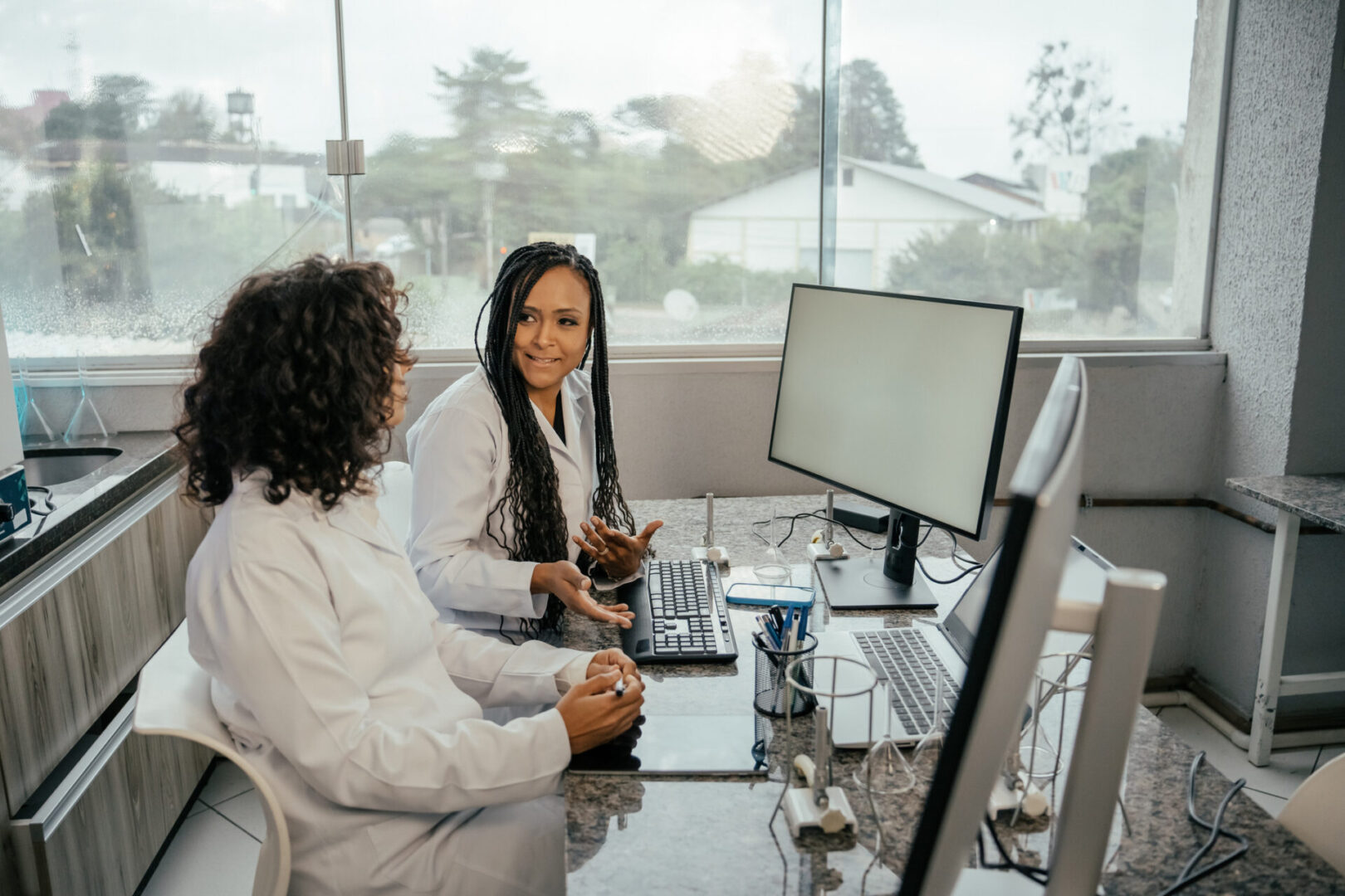 Two professionals discuss work at a computer in an office.