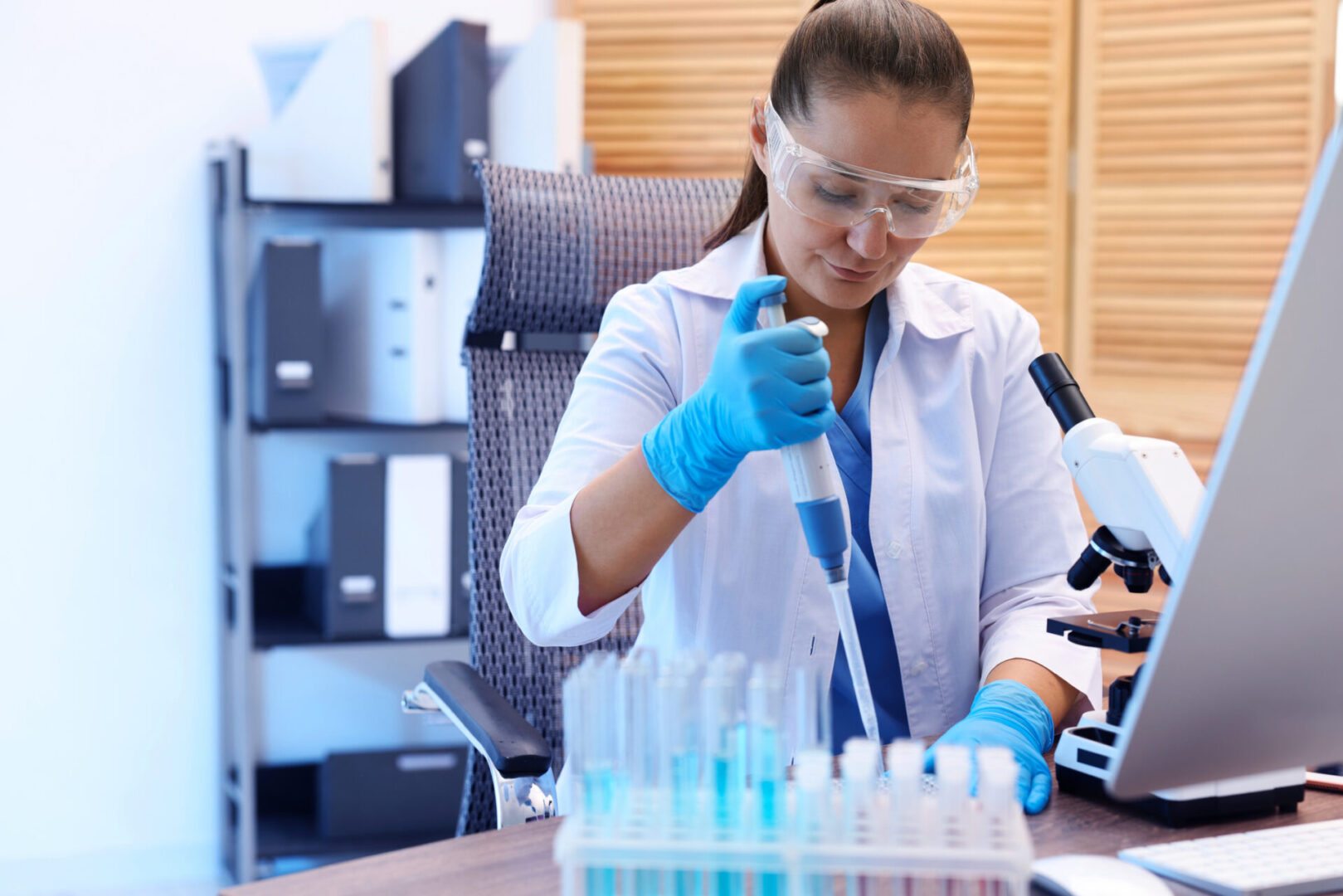 Scientist in lab using pipette to transfer liquid into test tubes.