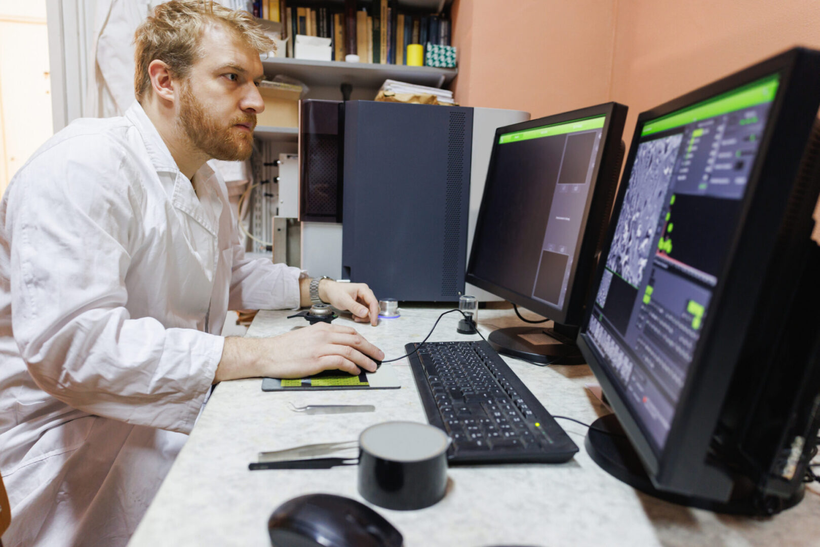 A man working on multiple computer monitors in an office.